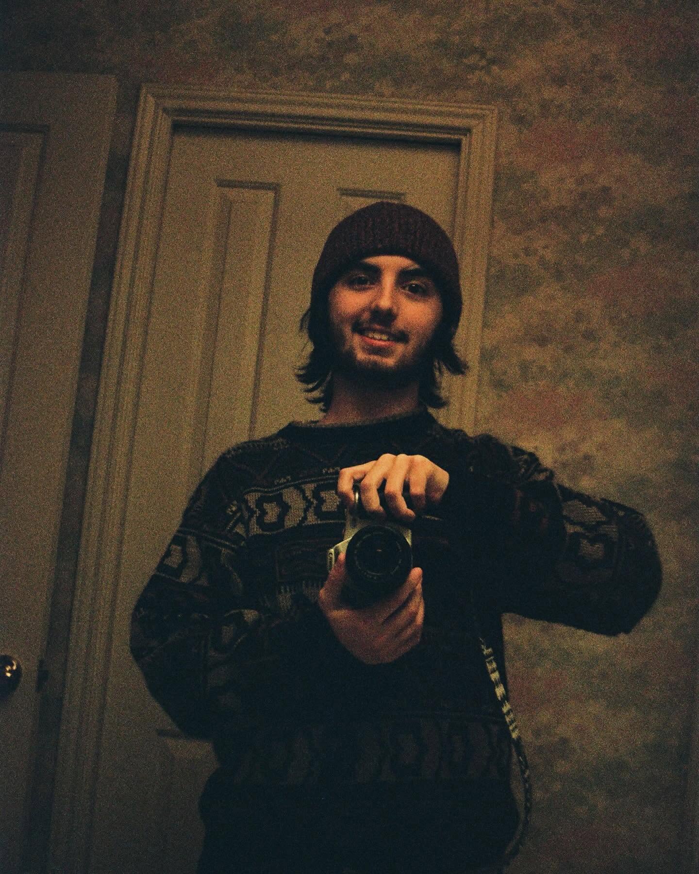 Sam taking a mirror selfie in a beanie